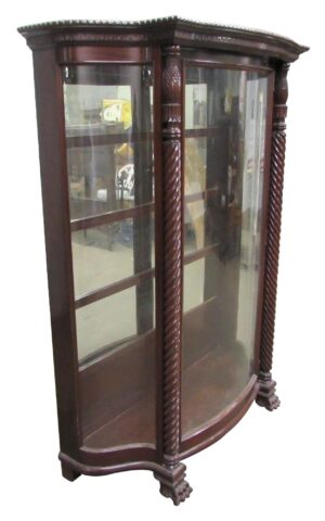 Spanish Revival curio cabinet with curved glass panels, carved columns, and claw feet, shown in a three-quarter view.