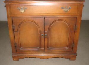 Traditional walnut storage hutch with a center drawer, lower cabinet doors, and original brass hardware.