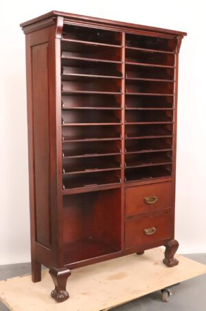Antique sheet music cabinet with two columns of narrow cubbies, a lower open compartment, and two drawers with brass pulls.