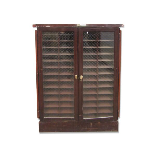 Commercial wood cabinet with two chicken wire glass doors, brass hardware, and slatted shelves visible behind the doors.