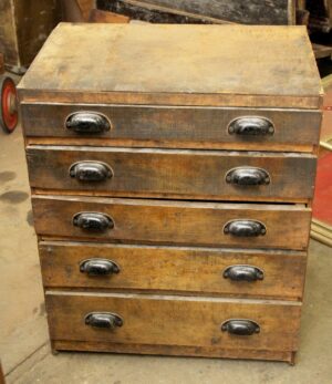 Vintage industrial chest of drawers with five drawers and black steel bin pulls, shown front view with heavy surface wear and staining on the dark wood tone finish.