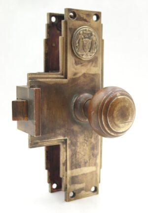 Antique bronze monolock door knob set with an Art Deco backplate, round knob, and visible latch piece.