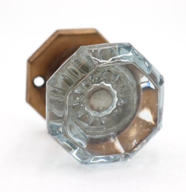 Close-up of an octagon clear glass dummy door knob with an antique brass rosette, shown from the underside.