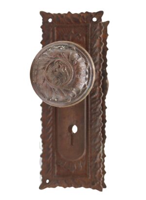 Antique Victorian passage door knob set with an ornate back plate, keyhole cutout, and a round knob in front view.