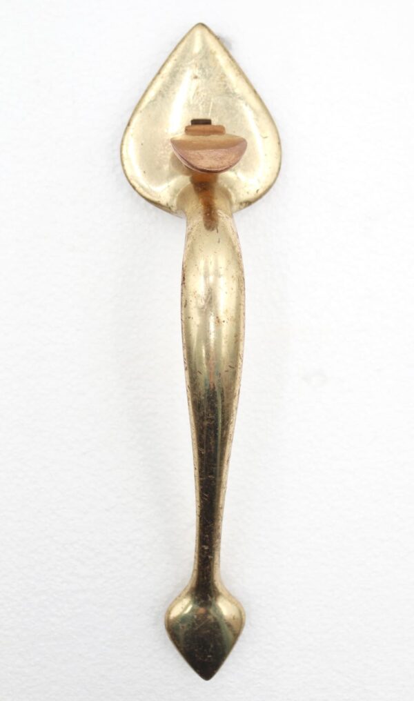 Polished brass door pull handle with a spade back plate and thumb latch, shown vertically with surface wear visible.