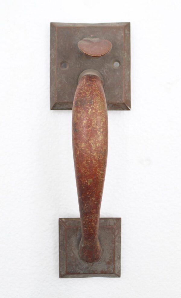 Vintage brass thumb latch door pull with a curved handle and square plates, shown front on with two mounting holes visible.