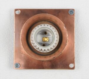 Copper-finish brass flush mount light with a square backplate, round center opening, and exposed socket assembly visible from the front.
