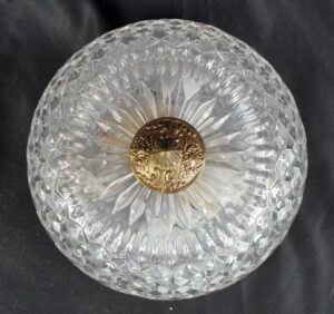 Crystal flush mount light with a clear faceted dome and an ornate brass center medallion.