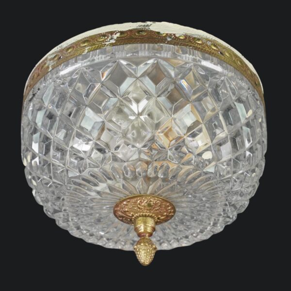 Crystal flush mount light with a faceted clear shade, ornate brass rim, and hanging pineapple finial.