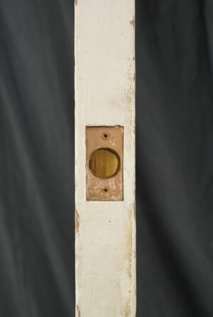 Close-up of a white wooden French door edge with an empty round hardware cutout and visible surface wear, showing no attached hardware.