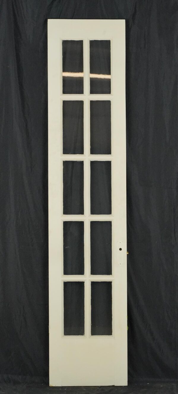 Tall white wood French door with ten glass panes and a brass mortise latch on the right edge.
