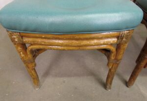 Close-up of a bamboo chair from a set of three, showing aqua vinyl upholstery and a medium wood tone bentwood frame.