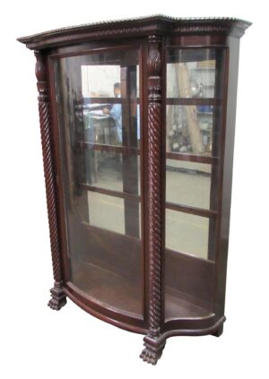 Spanish Revival curio cabinet with curved glass panels, dark wood tone, carved columns, and claw feet.