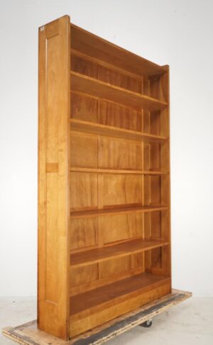 Six-shelf wooden bookcase in a medium wood tone, shown at an angle with open shelves and visible surface wear from prior use.