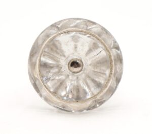 Clear round glass cabinet knob shown from the back with a central steel screw hole and visible surface wear.