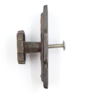 Side view of a vintage cabinet knob with a hammered texture, antique brass finish, and mounting screw attached.