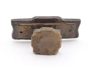 Two vintage cabinet knobs with an antique brass finish, showing a hammered texture and mounting holes on the back.