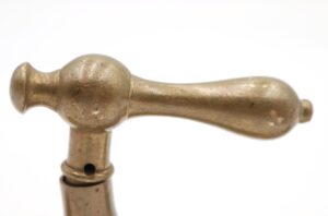 Close-up of a vintage brass passage door lever with an antique finish, showing the rounded handle and spindle opening.