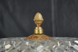 Close-up of a crystal flush mount light with an ornate brass finial and clear crystal rim visible.