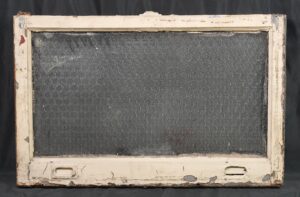 Rectangular reclaimed window with a worn white wood frame and a clear wormy chicken wire glass pane.