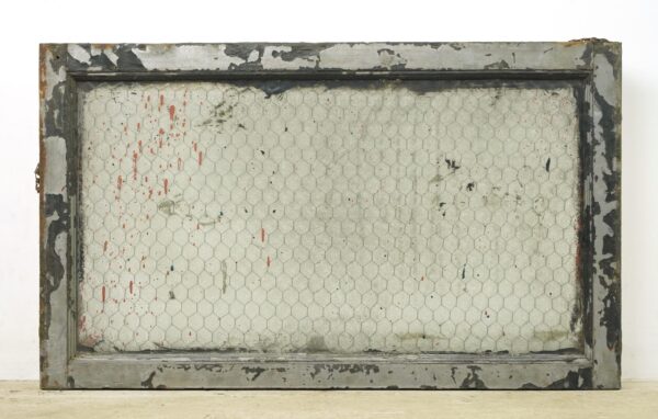 Rectangular reclaimed window with a worn wood frame and clear chicken wire glass pane, showing chipped paint and rusted surface wear.