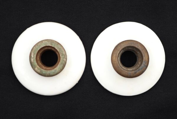 Pair of vintage door knob rosettes with white ceramic faces and brass collars, shown as a pair from the front.