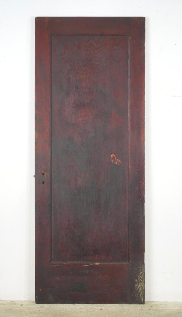 Vintage wood passage door with one full-length panel and an original brass mortise, shown front view with visible surface wear and cracks.