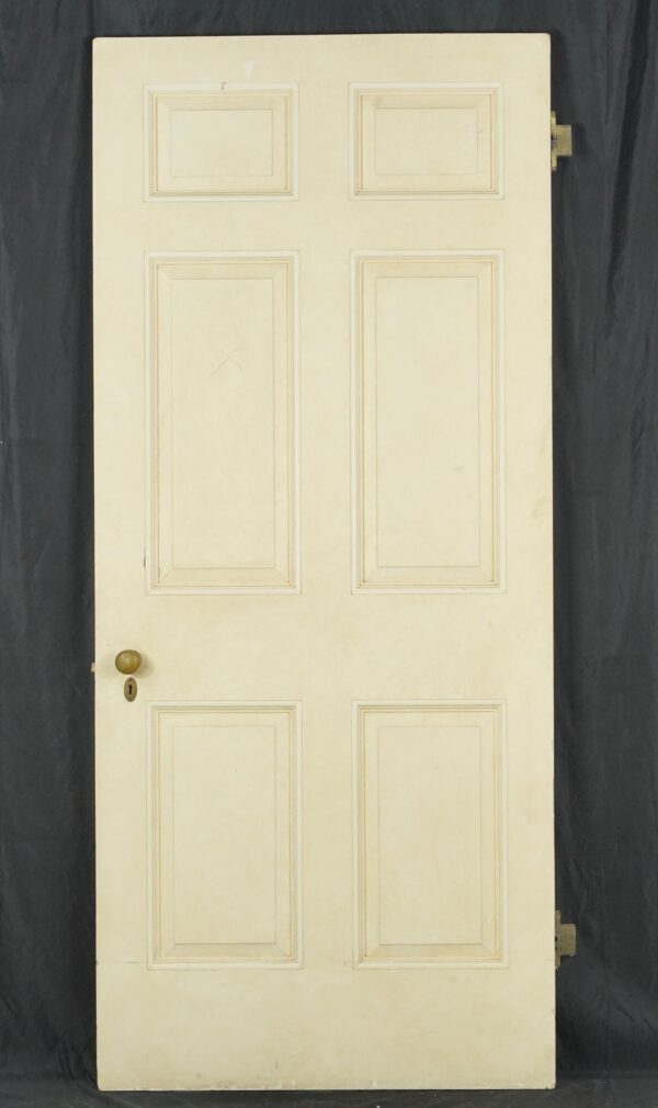 Vintage white wood passage door with six panels, brass knob, mortise lock, and hinges visible on the edge.