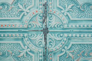 Handcrafted blue tin wall panel with ornate four-quadrant embossed detail and a central seam.