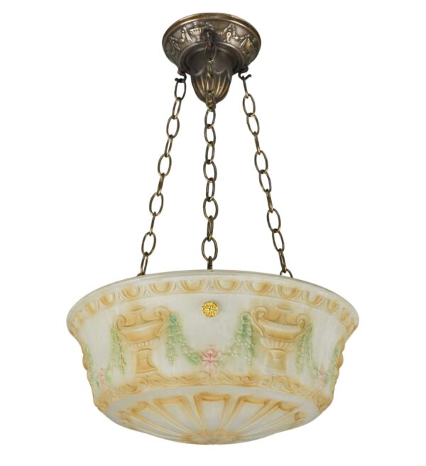 Neoclassical pendant light with a white cast glass dome shade, decorative raised urn and vine motifs in tan, green, and pink, suspended from three chains with a brass canopy.