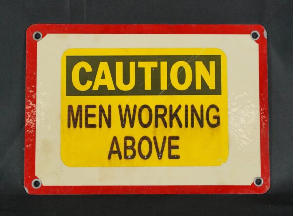 Steel caution wall sign with four mounting holes, reading “Caution Men Working Above” in black and yellow with a red border.