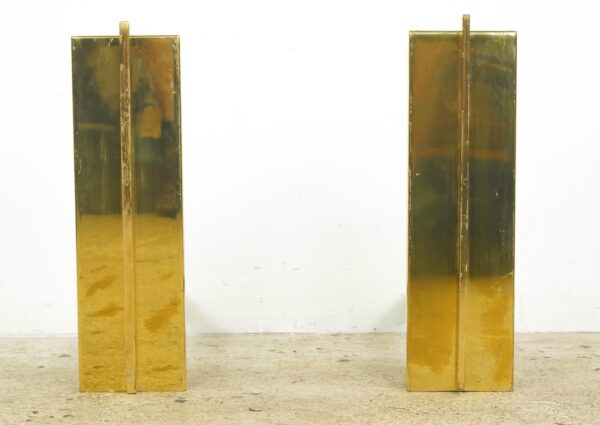 Pair of tall brass fireplace andirons with rectangular panels and visible surface wear, shown as a matching pair.