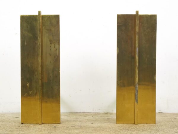 Pair of polished brass fireplace andirons shown as two tall rectangular panels with visible surface wear.