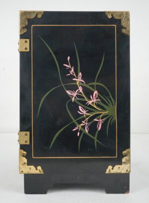 Hand-painted black lacquer cabinet with polished brass corner guards, hinges, and a floral motif on the front.