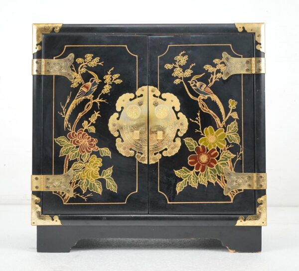 Front view of a black lacquer cabinet with hand painted bird and flower motifs, polished brass corner guards and hinges, and a decorative central medallion with round pulls.