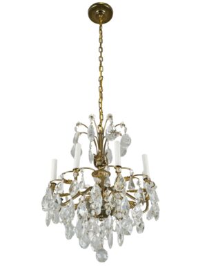 French eight-arm chandelier with a brass frame, clear teardrop crystals, and a long chain hanging from the ceiling mount.