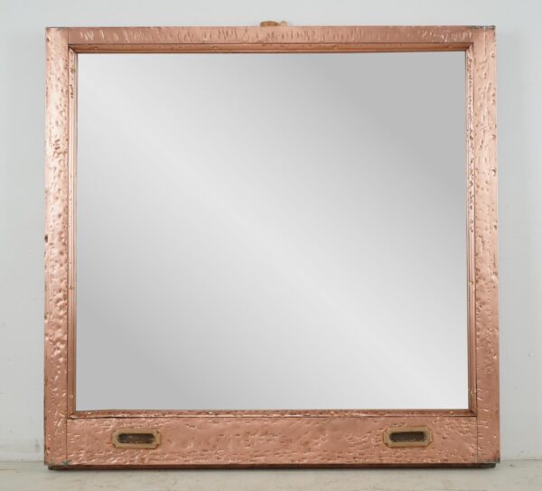Square mirror in a salvaged copper window frame with a rectangular lower panel and two inset handle details.