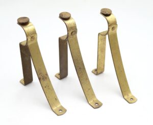 Set of three antique brass curtain rod brackets with circular fronts and elongated mounting arms, shown with surface wear and no screws included.