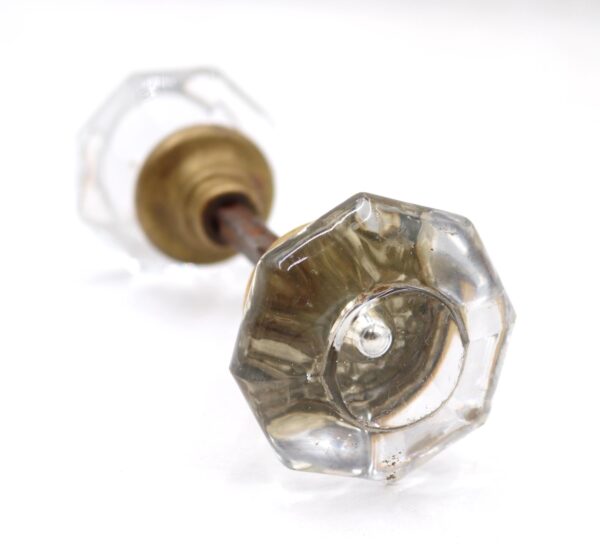 Clear octagon glass door knob with a center bullet and brass shank, shown in close-up on a spindle.