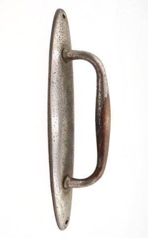 Vintage door pull with an oval back plate and curved handle, shown front on with heavy surface wear.