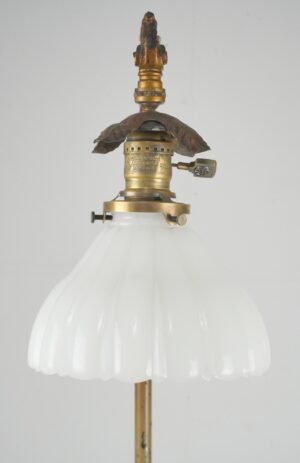 Victorian bridge floor lamp with an antique brass finish and a fluted white milk glass shade shown in a close-up of the top assembly.