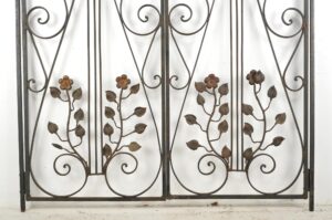 Two-panel wrought iron gate with scrollwork and ivy vine details, shown frontally with surface wear and a few missing leaves, priced as a pair.