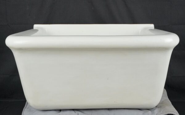White fireclay utility sink basin with a wide rounded rim and rectangular front view, showing heavy surface wear and minor marks.