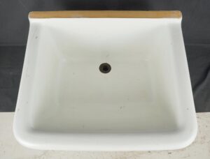 White utility sink basin with a central drain opening and a top rim, shown from above with visible surface wear and small marks.