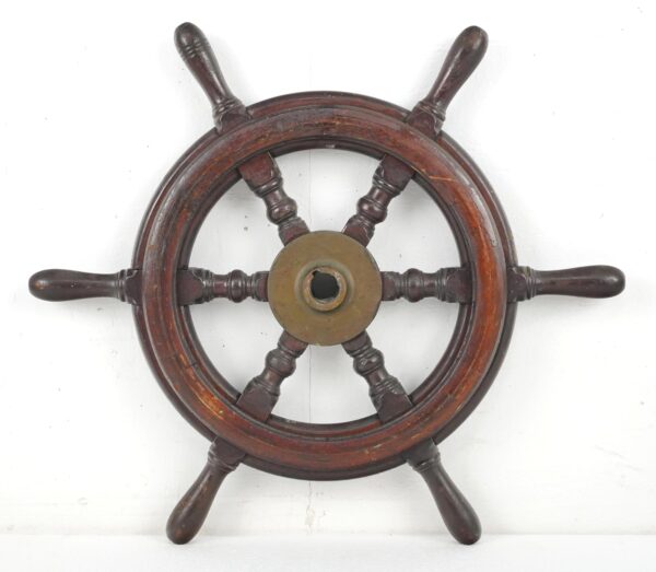 Vintage wood ship steering wheel with six spokes and a brass center hub, shown front view with visible surface wear.