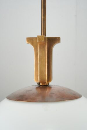 Close-up of a pendant light showing the brushed brass fitter mounted on the white glass globe.