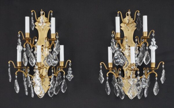 Pair of French wall sconces with brushed brass frames and clear crystal pendants, shown side by side.