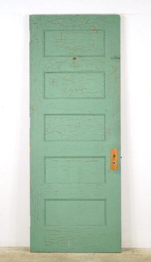 Vintage five-panel passage door with cracked green paint, decorative trim, and an attached brass lock plate visible on the right side.