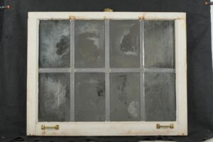 Reclaimed wood window mirror with eight panes, worn silvering, and original brass hardware on the bottom rail.