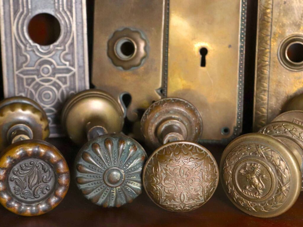 A close-up view shows intricately engraved vintage brass doorknobs and keyhole plates, their ornate patterns and craftsmanship visible in the detailed metalwork.